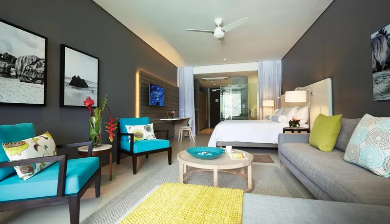 Un salon lumineux s'ouvre sur une chambre avec un grand lit.