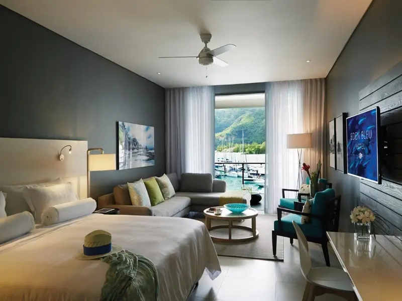 Une chambre lumineuse avec un lit, un canapé et une vue sur un port de plaisance.