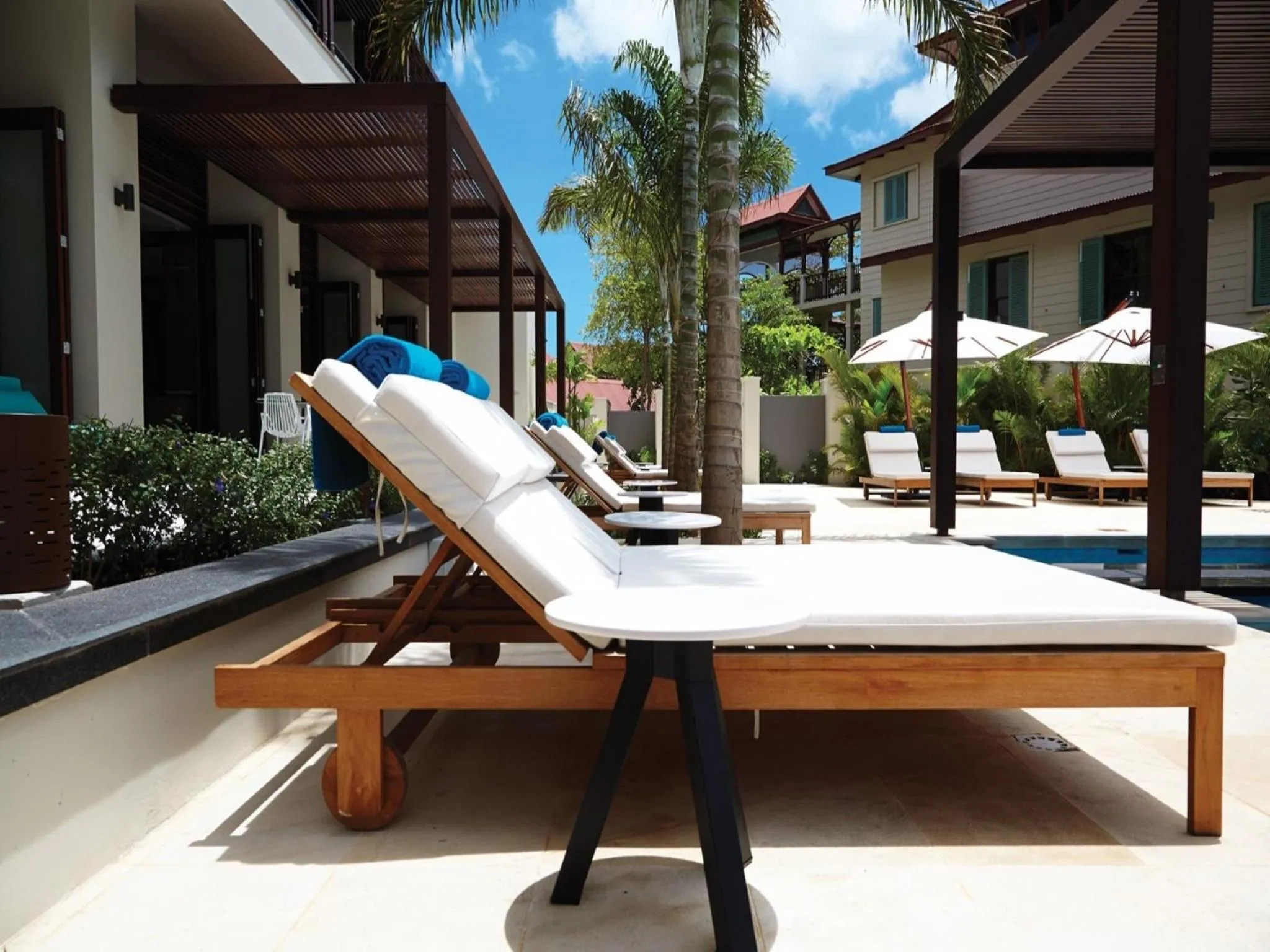 Transats blancs disposés sur une terrasse ensoleillée près d'une piscine.