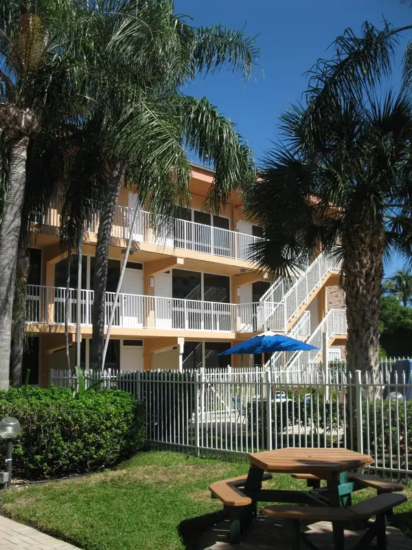 Bâtiment à balcons et végétation tropicale, avec table de pique-nique au premier plan.