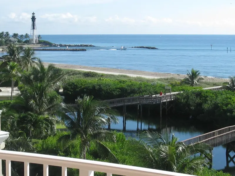 Vue sur une plage bordée de palmiers et un canal.