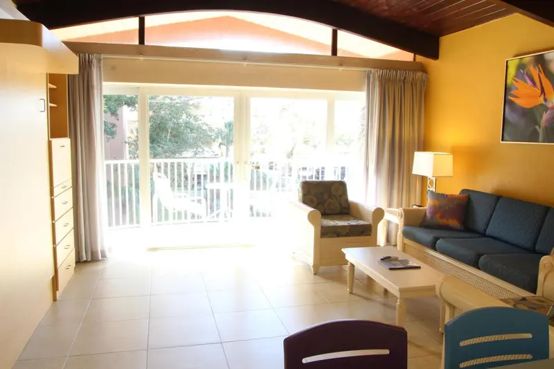 Espace de séjour lumineux avec canapé et fauteuil donnant sur une terrasse.