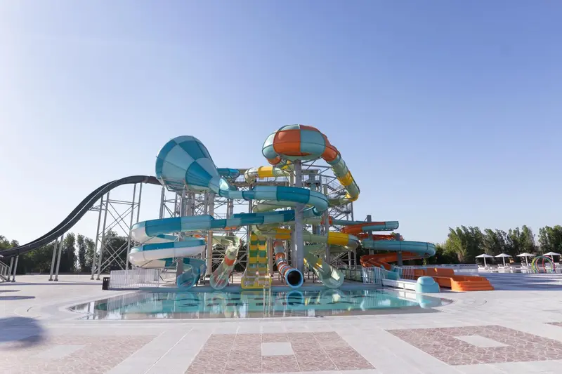 Toboggans aquatiques colorés s'élèvent au-dessus d'une piscine ensoleillée.