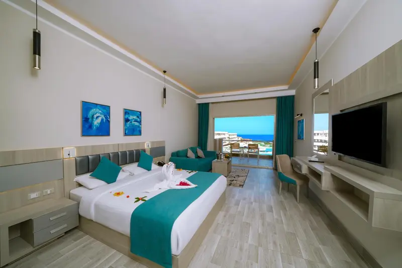 Chambre lumineuse avec un lit double et une vue sur la mer.