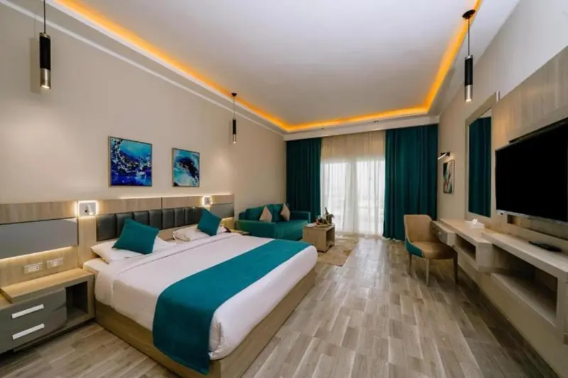 Chambre lumineuse avec un grand lit et un coin salon.