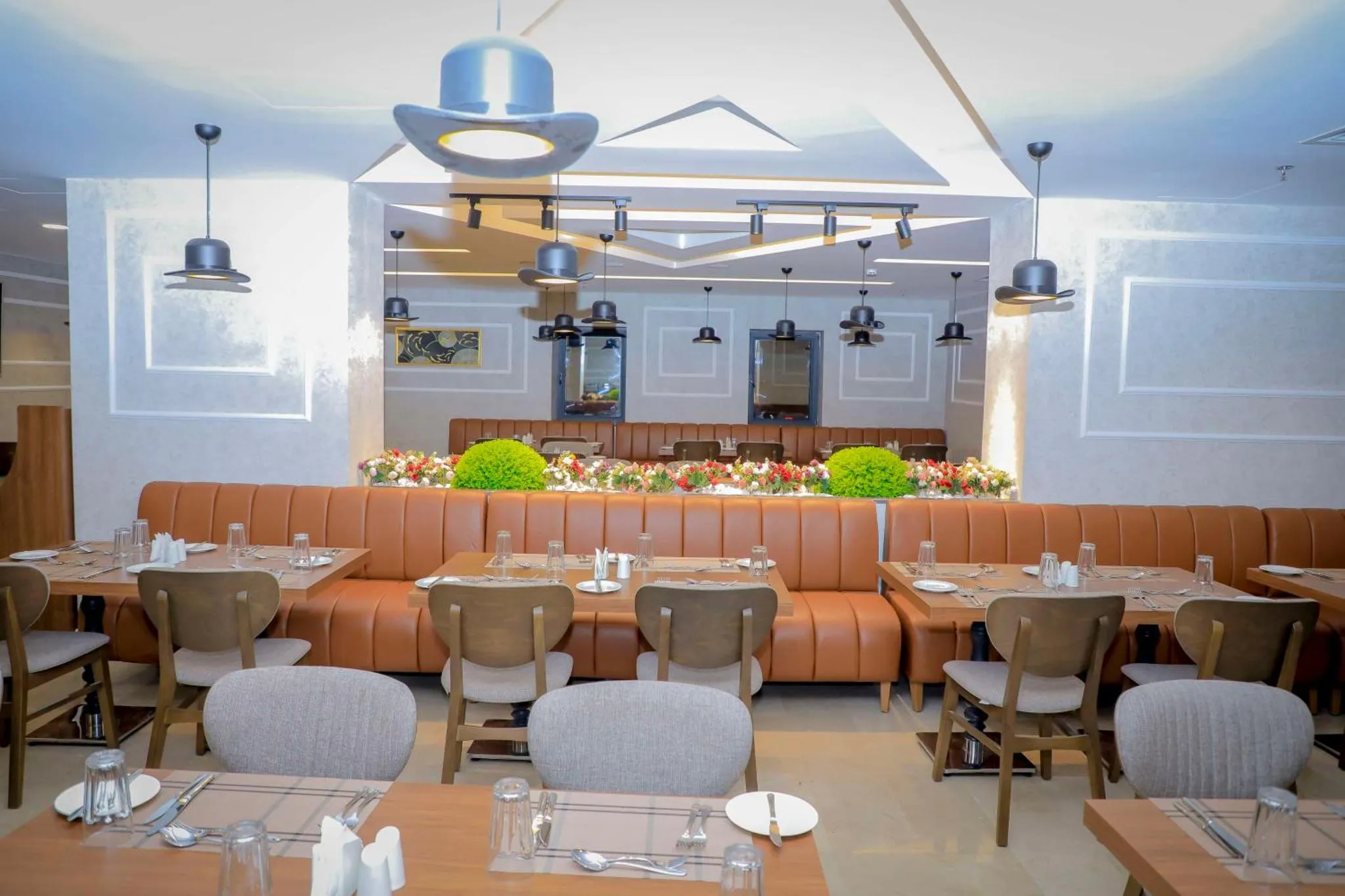 Une salle de restaurant lumineuse avec des tables dressées et des banquettes en cuir.