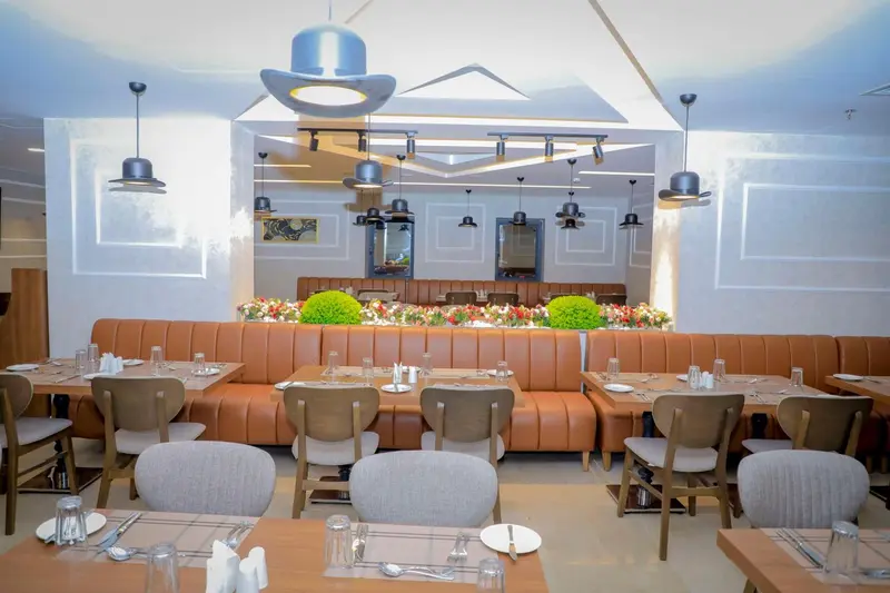 Une salle de restaurant lumineuse avec des tables dressées et des banquettes en cuir.