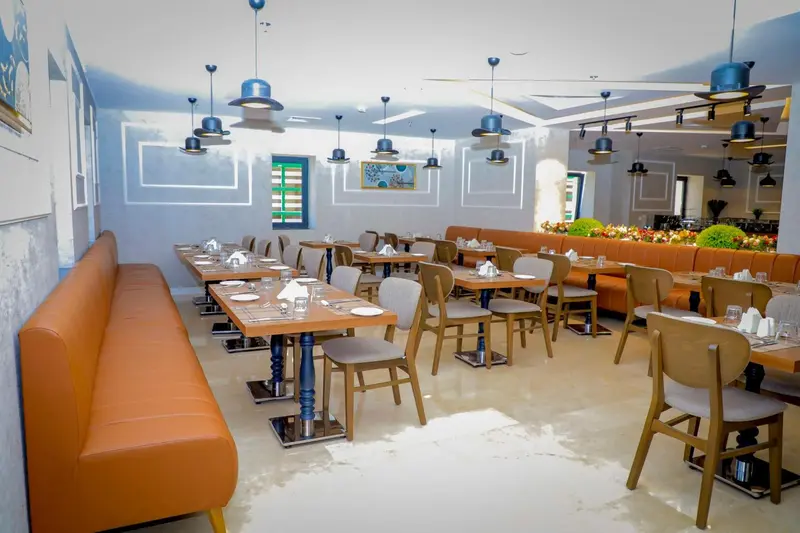 Une salle de restaurant lumineuse avec des tables dressées et des banquettes en cuir.