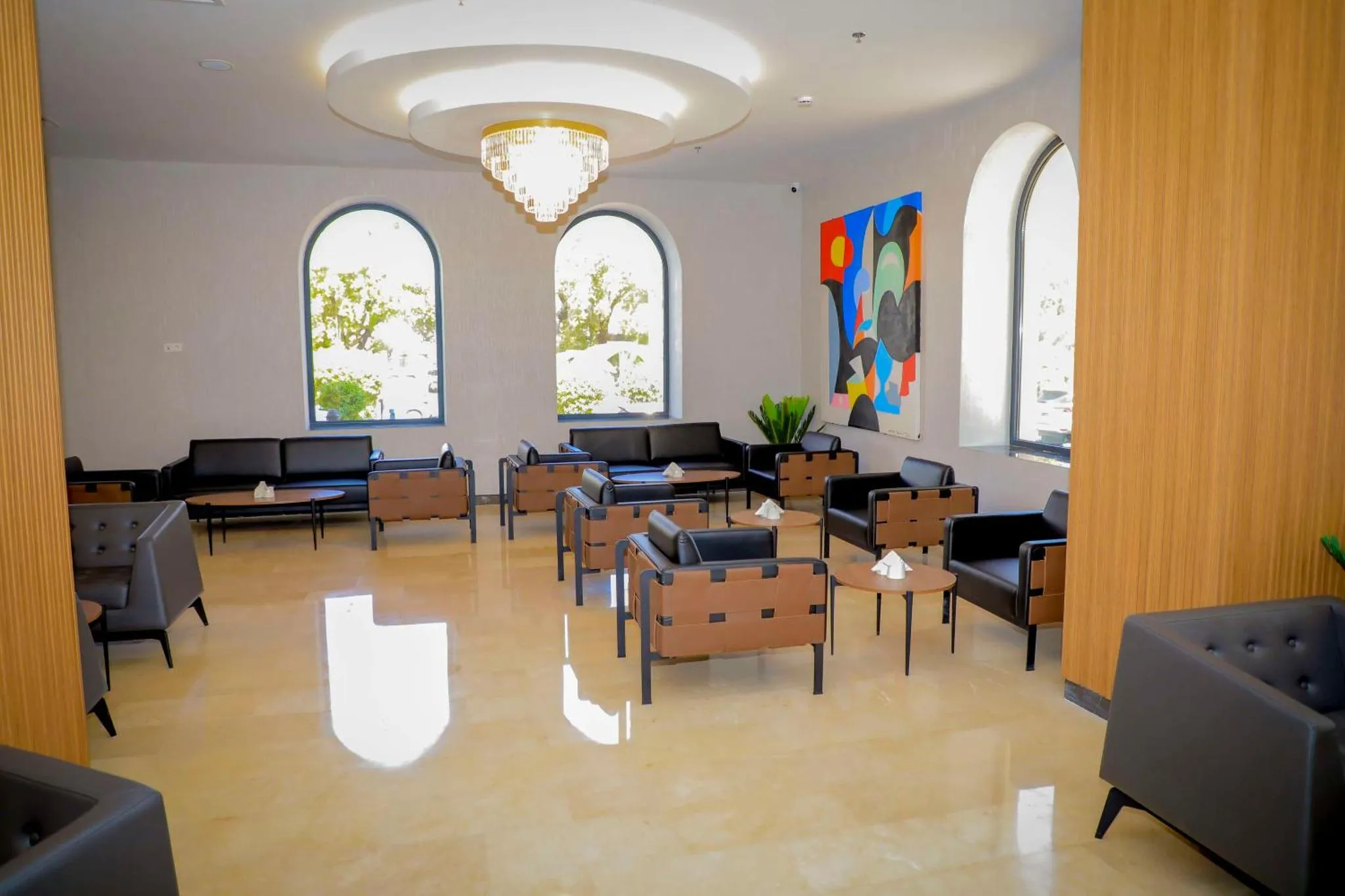 Espace de détente lumineux avec canapés et fauteuils noirs.