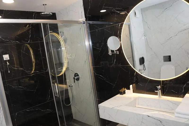 Une salle de bain moderne avec une douche à l'italienne et un grand miroir.