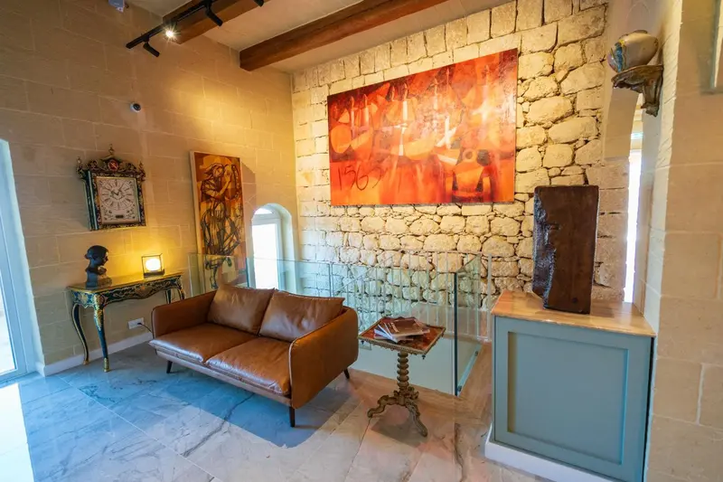 Un canapé en cuir marron se trouve dans un espace intérieur décoré de pierres apparentes et d'œuvres d'art.