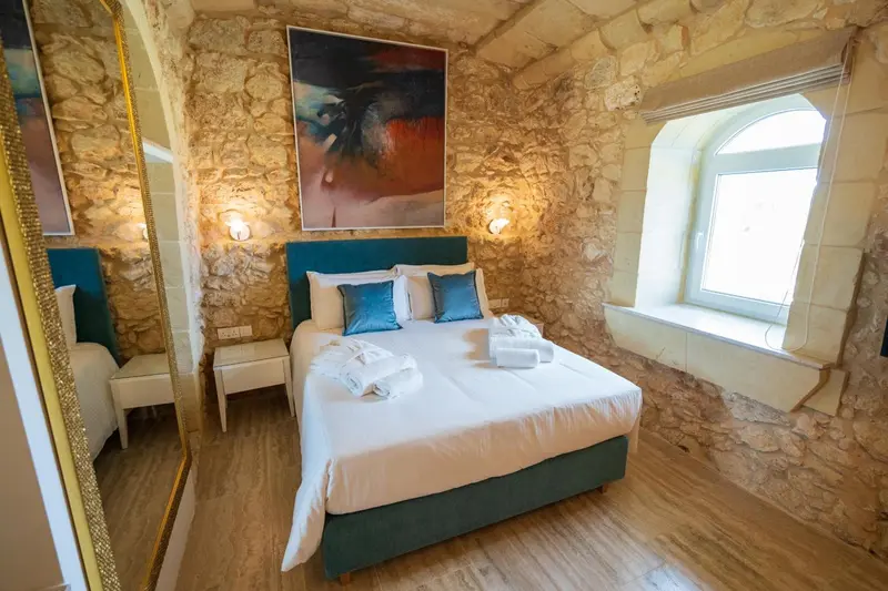 Une chambre à coucher avec un lit double et un mur en pierre.