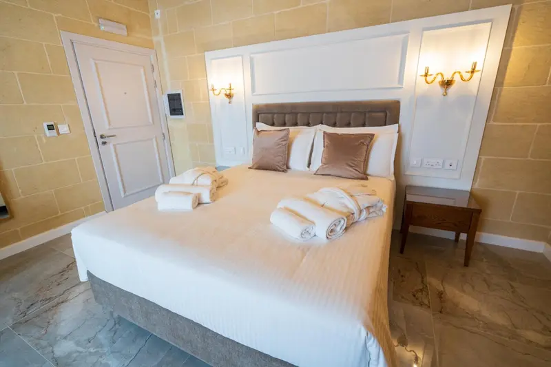 Une chambre lumineuse avec un grand lit recouvert d'une couette blanche et de coussins.