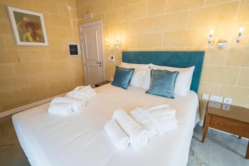 Une chambre lumineuse avec un grand lit recouvert de linge blanc et de coussins.