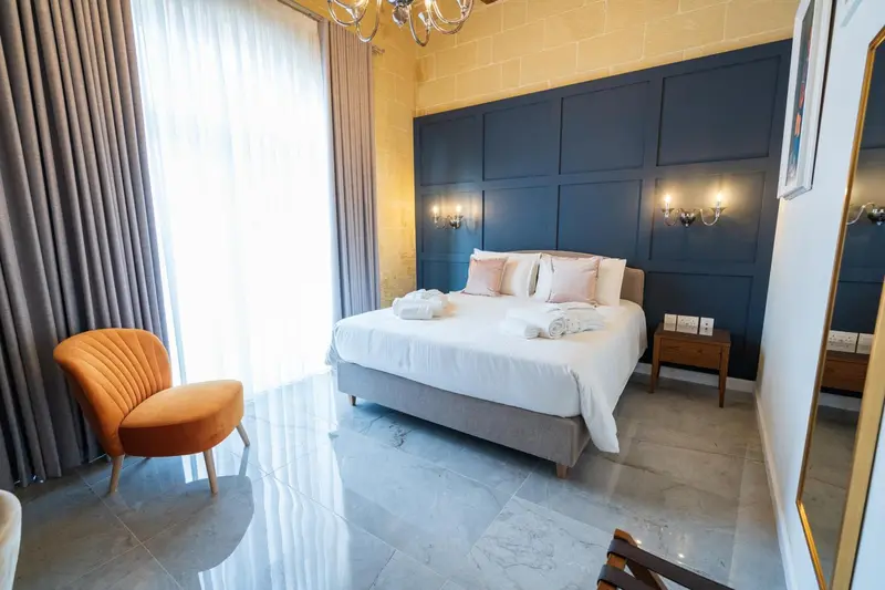 Une chambre lumineuse avec un grand lit et un fauteuil.