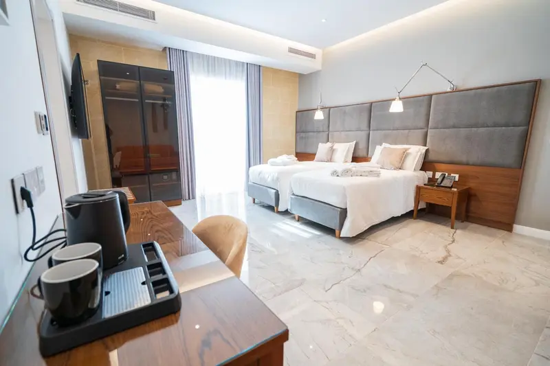 Une chambre lumineuse avec deux lits simples et un bureau.