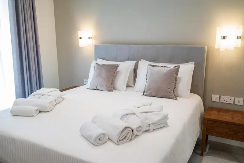 Un lit double est soigneusement fait avec des oreillers et des couvertures blanches.