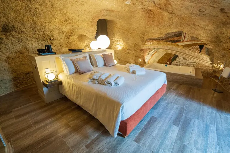 Une chambre troglodyte avec un lit double et une baignoire à remous.