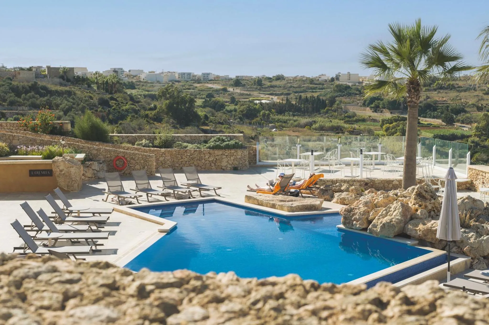 Terrasse avec transats et piscine au bord d'une vue sur la campagne.