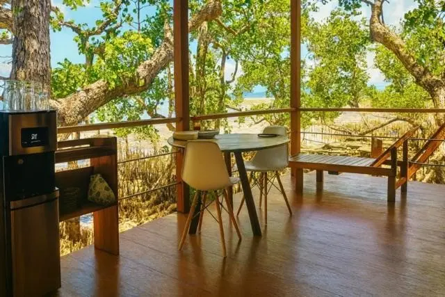 Une table et des chaises se trouvent sur une terrasse en bois avec vue sur la mer.