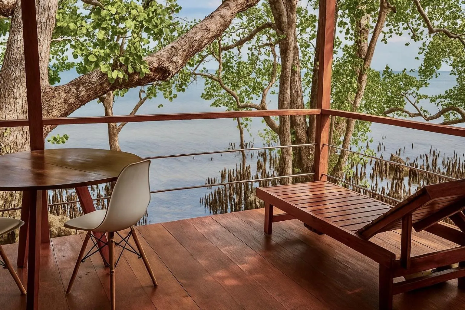 Terrasse en bois avec table, chaises et transat face à la mer.
