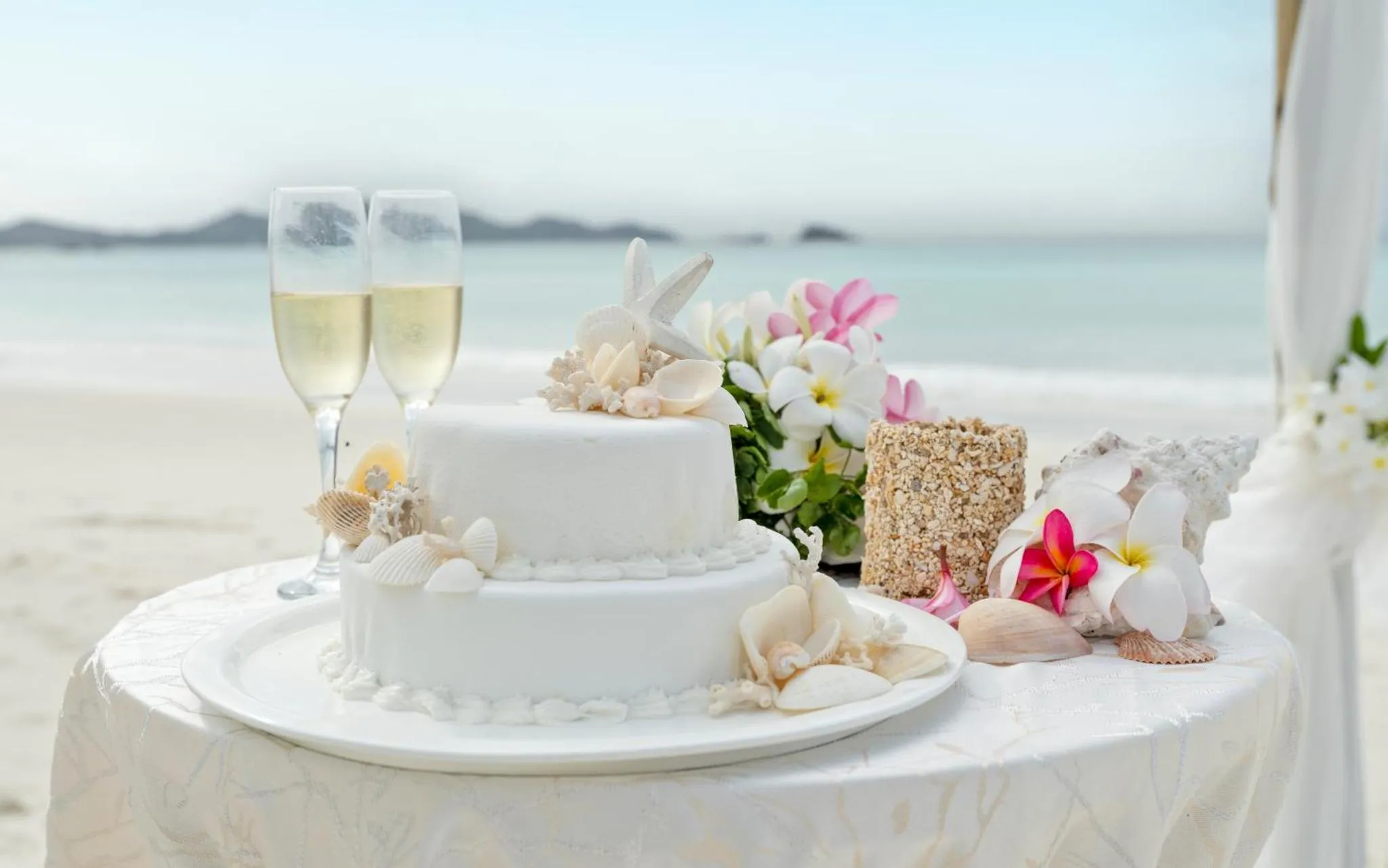 Une table décorée pour une célébration en bord de mer avec un gâteau à deux étages.