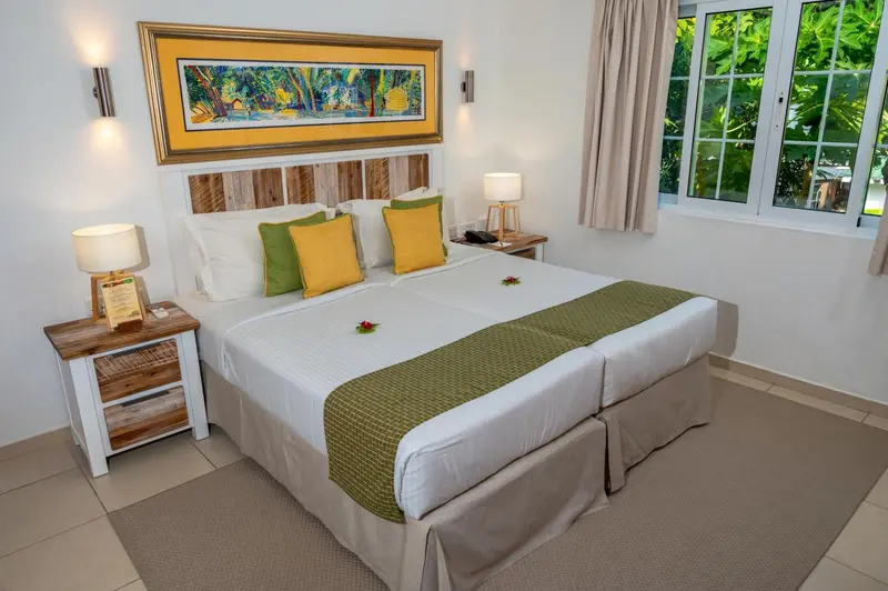 Une chambre lumineuse avec un grand lit recouvert d'une courtepointe verte et jaune.