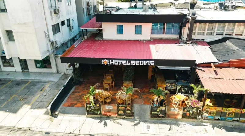 Façade d'un bâtiment avec une terrasse ombragée et des tables.