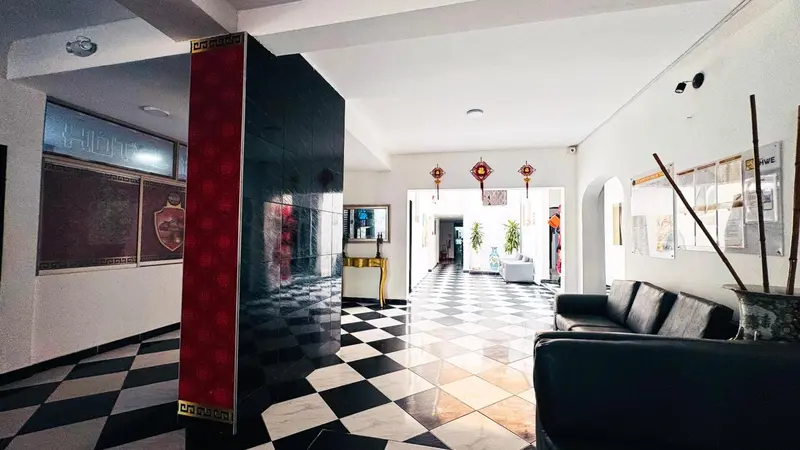 Un couloir d'hôtel lumineux avec un sol à carreaux et des canapés.