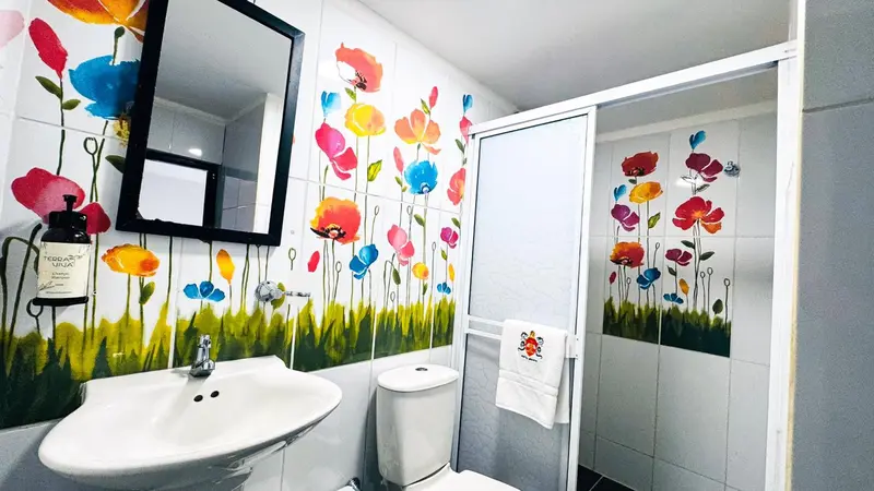 Une salle de bain lumineuse avec un lavabo et des carreaux muraux ornés de motifs floraux.