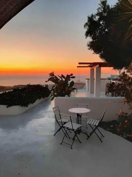 Terrasse avec mobilier d'extérieur et vue sur la mer au coucher du soleil.
