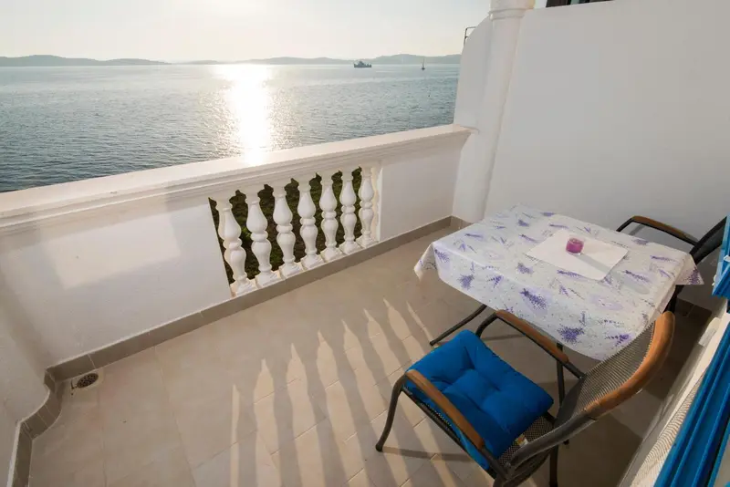 Une terrasse avec une table et des chaises offre une vue sur la mer scintillante.