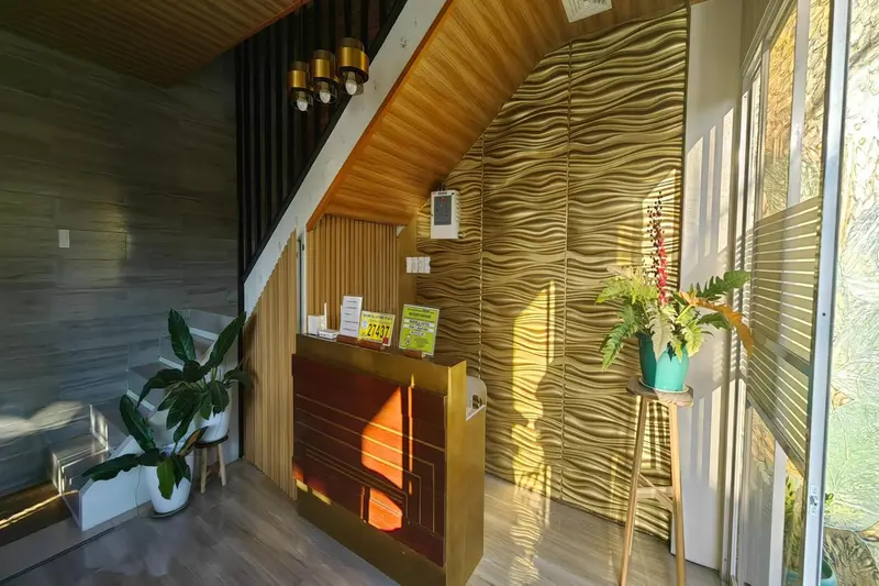 Un comptoir d'accueil lumineux avec une décoration murale texturée et des plantes.