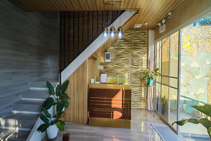 Un hall d'accueil lumineux avec un comptoir en bois et des plantes.