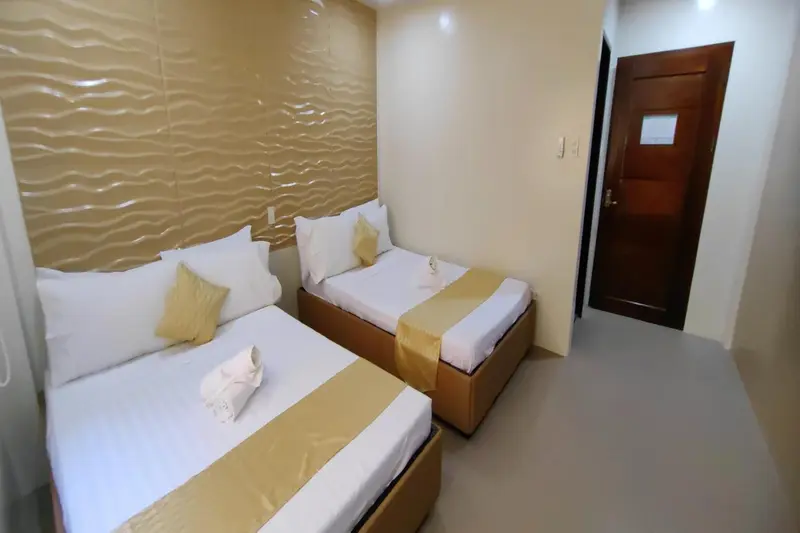 Une chambre lumineuse avec deux lits simples et une décoration beige et dorée.