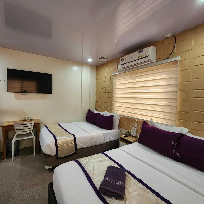 Une chambre lumineuse avec deux lits simples et un téléviseur mural.