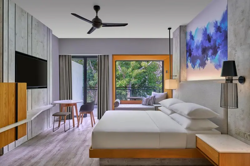 Une chambre lumineuse avec un grand lit et un accès à un balcon.