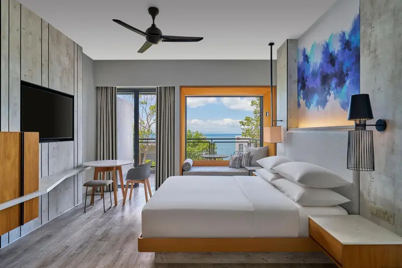 Chambre lumineuse avec un grand lit et vue sur la mer.