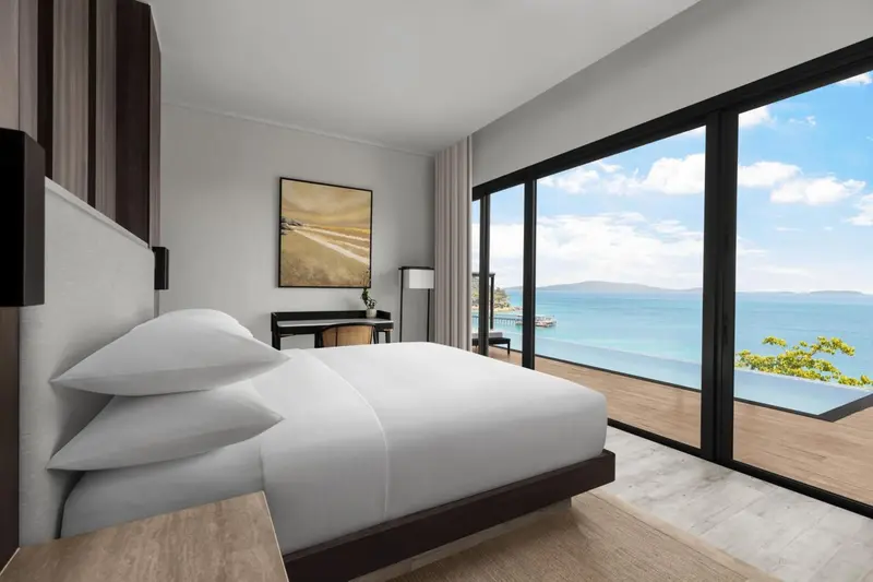 Chambre lumineuse avec un grand lit donnant sur une vue mer.