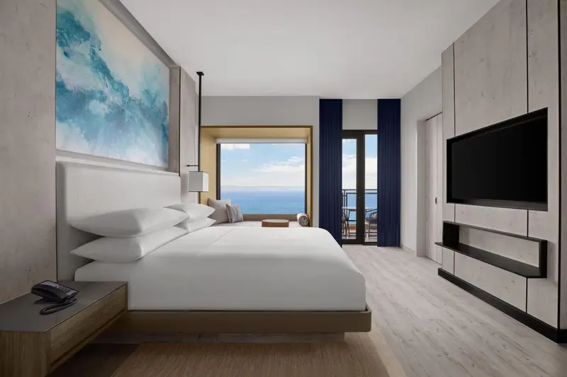 Chambre lumineuse avec un grand lit et vue sur la mer.