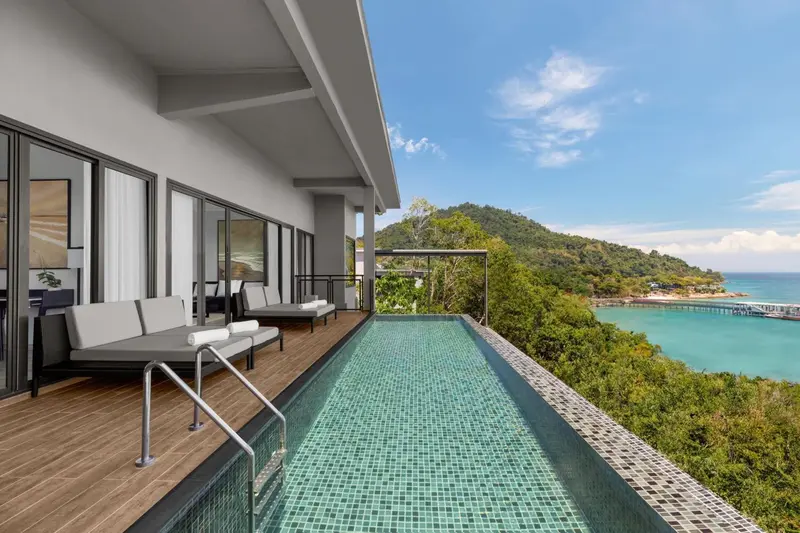 Terrasse avec piscine privative donnant sur la mer et la végétation.