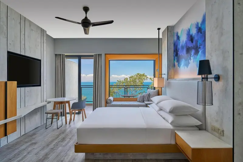 Chambre lumineuse avec un grand lit et vue sur la mer.
