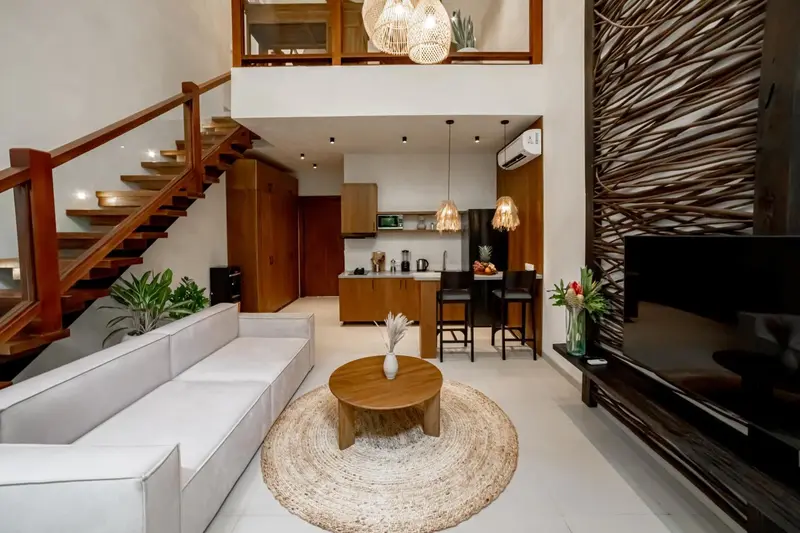 Espace de vie intérieur lumineux avec canapé, table basse et cuisine ouverte.