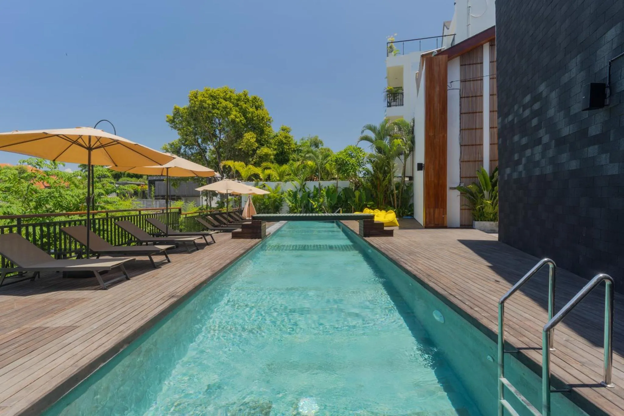 Une piscine rectangulaire bordée d'une terrasse en bois avec des transats.