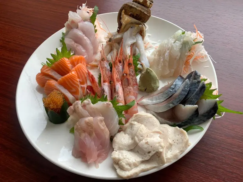 Assiette de fruits de mer crus variés présentée sur une table en bois.