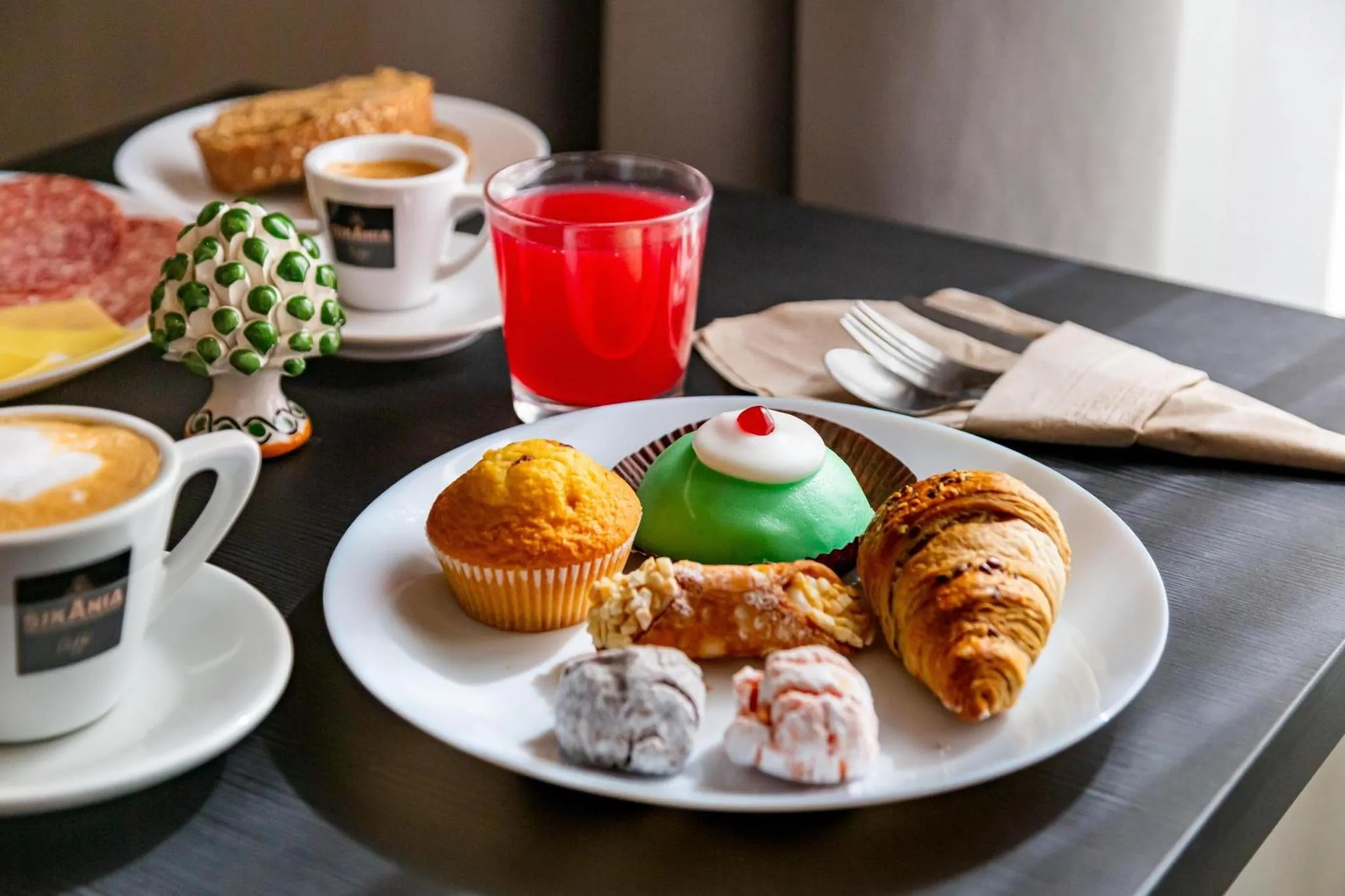 Une table présente un assortiment de pâtisseries, de viennoiseries et de boissons.
