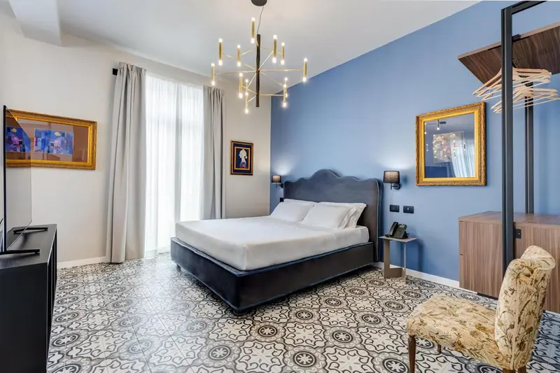 Une chambre lumineuse avec un grand lit et un décor mural bleu.