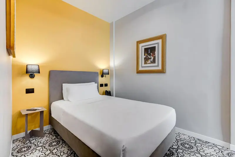 Une chambre lumineuse avec un lit simple et un mur jaune.