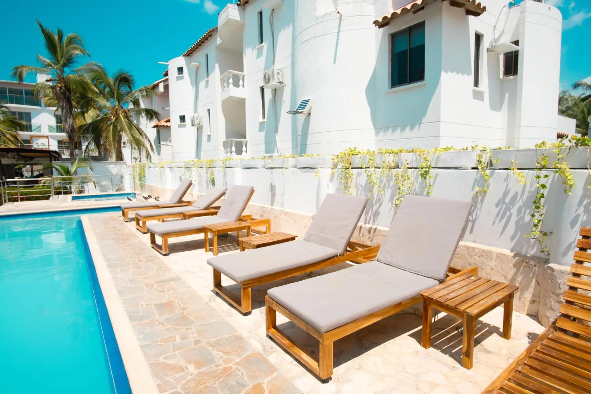 Transats alignés au bord d'une piscine turquoise dans un cadre ensoleillé.