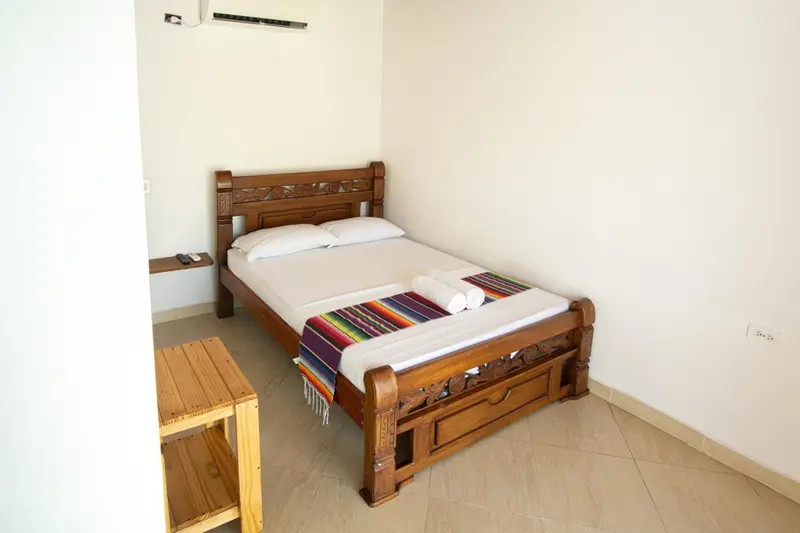Une chambre lumineuse avec un lit en bois sculpté et une décoration colorée.